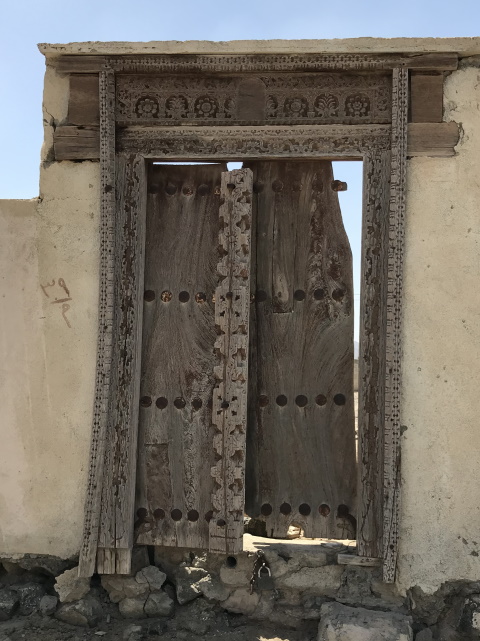 Wooden Omani door on ruined house